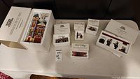Whole lot of Department 56 Christmas in the City and Snow Village items in original boxes on table