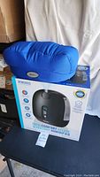 Box of Homedics TotalComfort Deluxe Ultrasonic Humidifier with blue BWell massager pillow on top