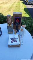 Photo showing all four figurines on a table: owl on base, Amish man in box, angel, and star ornament box.