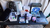 Full overview of lot including neck massagers, skincare masks, hair rollers, foot care products, aromatherapy jars, pillow, candles, and magnifying mirror.