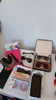 Photo showing assortment of sunglasses and cases on white table