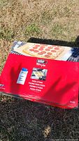Box of the Weber Style pizza stone showing branding, pizza photo, and multilingual labeling.