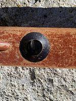 Close-up photo of black circular end cap on antique cherry wood level.