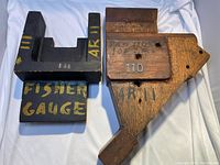 Two wooden industrial molds laid side-by-side, one painted black with yellow lettering, the other unpainted with visible markings and holes.