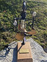 Front view of industrial salvage light with wooden base and visible steam gauges, nautical propeller, and Edison bulb in wire cage.