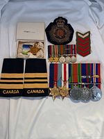 All lot contents arranged on white background: boxed Atlantic Star, cap badge, chevron, flashes, miniature and full-size medal groups
