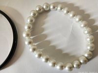 Photo of faux pearl bead bracelet showing round white beads strung on elastic or wire.