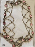 Full view of silver-tone belt with pink oval-shaped stones linked by chain forming decorative lattice pattern.