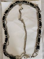 Full view of the black belt showing chain and faux leather weave, metal clasp end.