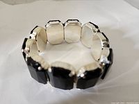 Overall view of black stone bracelet showing linked stretch segments with silver backing