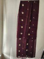 Full view of maroon scarf or wrap showing jewel embellishments arranged in circular patterns on the fabric.