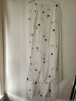 Full view of ivory scarf/wrap, hanging vertically, showing sheer fabric with scattered embroidered motifs.