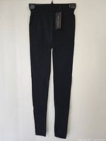 Front view of full length black stretch pants on hanger with brand tag visible.