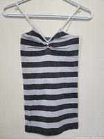 Front view of sleeveless ladies top with horizontal black and white stripes on hanger.