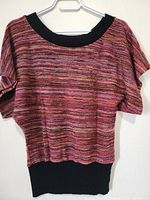 Front view of ladies knit top showing multicolored horizontal stripes with black ribbed neckline and ribbed hem.