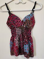 Front view of the ladies top showing multicolor paisley pattern, V-neck neckline, and gathered elastic waistband.