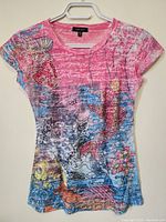 Front view of the ladies top showing the colorful pattern design and jewel decorations on the upper left chest and shoulder.