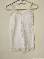Full front view of the white ladies top showing lace detailing and spaghetti straps.