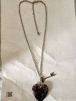 Full view of the silver chain necklace featuring the heart-shaped leopard print pendant and key pendant.