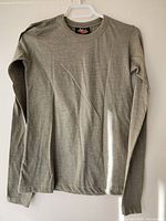 Front view of the olive long sleeve top hanging on a hanger showing full garment details.