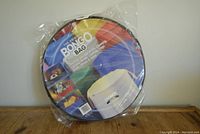 The Original Bongo Bag storage organizer in round packaging showing colorful label and images of use.