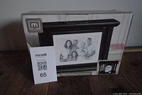 Photo of the boxed black revolving photo clock showing the product image on the front of the packaging.