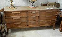 Front view of the 9 drawer wooden dresser with recessed handles and mid-century style legs.