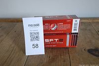 Two boxes of Nike SFT2 golf balls stacked on wood surface with a MaxSold lot number card visible