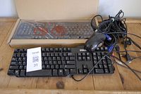 Photo showing Lenovo keyboard in box wrapped in plastic, used Dell keyboard, and various cords including USB and VGA cables with a wired optical mouse.