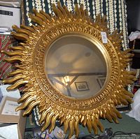 Full view of the large sun-shaped mirror showing the gold ornate frame and central reflective surface.