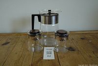 Full front view of the MCM style glass coffee pot with two small glass carafes on wood table.