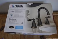 Box front showing Moen logo, Banbury line, model CA84924BRB, brushed bronze finish and faucet image.