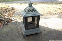Front view of the metal fire pit showing mesh sides and square base