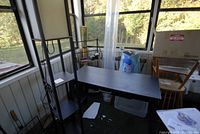 Desk and floor lamp in an enclosed porch area, showing overall condition and scale relative to other furniture.