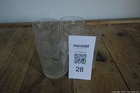 Four vintage drinking glasses with etched floral or leaf pattern grouped together on a table.