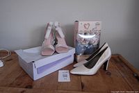 Photo showing three pairs of women's footwear: white satin pumps with tags, pink sparkly sandals on top of a shoebox, and Totes slippers in original box.