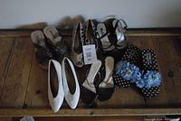 Overview of six pairs of women's shoes on wooden floor.