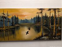 Full front view of the original canvas painting showing a nature landscape with pine trees, water, flying birds, and a sunset.