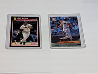 Two Barry Bonds baseball cards in plastic sleeves against a white background. One is a Score 91 card showing Bonds running, the other a Topps Stadium Club card showing Bonds batting.