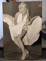 Frontal photo of large black and white print of Marilyn Monroe in iconic blown dress pose, mounted on wood panel