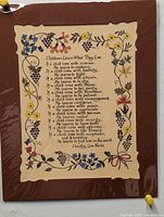 Photo of wall art print titled 'Children Learn What They Live' with floral border mounted on brown backing under clear sleeve.