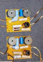 Top side photo showing two yellow PCB crossover networks each with inductors, capacitors, and resistors mounted.