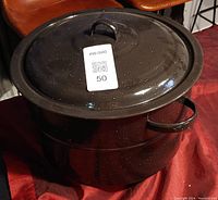 Black enamel large cooking pot with lid and handles, speckled white finish.