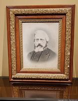 Front view of vintage black-and-white portrait framed by an ornate multi-layered wood and gold trimmed frame.