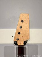 Close-up of the natural finish headstock with four tuning peg holes showing wood grain details