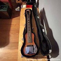 Top view showing SX lap steel guitar inside hard case, highlighting the mahogany body, single pickup, and metal bridge cover with SX logo.