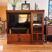 Front view of the solid wood TV cabinet with a large central TV space, glass door shelving on right, and lower closed doors.