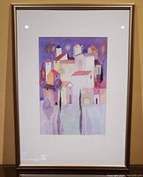 Front view of the framed print showing the colorful urban buildings artwork and gold frame.