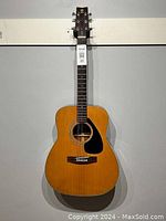 Full front view of vintage Yamaha acoustic guitar showing natural wood finish, black pickguard, and Yamaha logo on headstock.