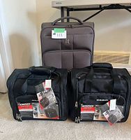 Front view showing one brown upright bag behind two black under-seat cases